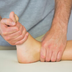 Physiotherapist examining patients foot in bright office Physiotherapist examining patients foot in bright office